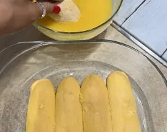 Step <p><span style="font-weight: normal;">Remoje brevemente la mitad de los bizcochos de soletilla en el zumo de naranja, lo justo para que se empapen sin romperse y vaya colocándolos en el fondo de una fuente rectangular (23 cm x 15 cm x 8 cm). O bien también en vasitos individuales. </span></p> illustration